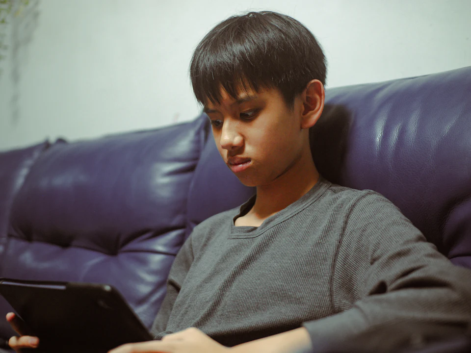 Un adolescente lee con atención en una tableta.
