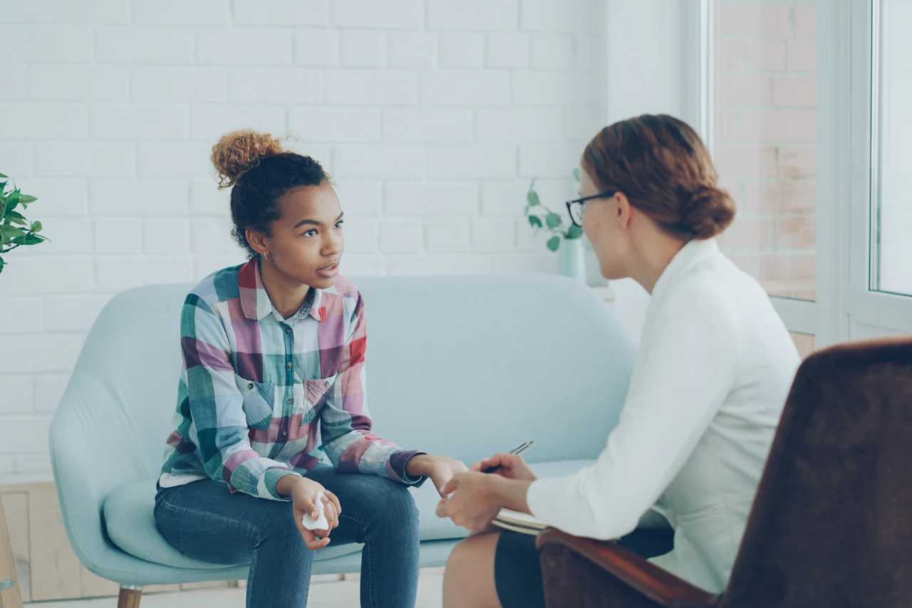 Una profesional conversa con una joven en un consultorio luminoso.