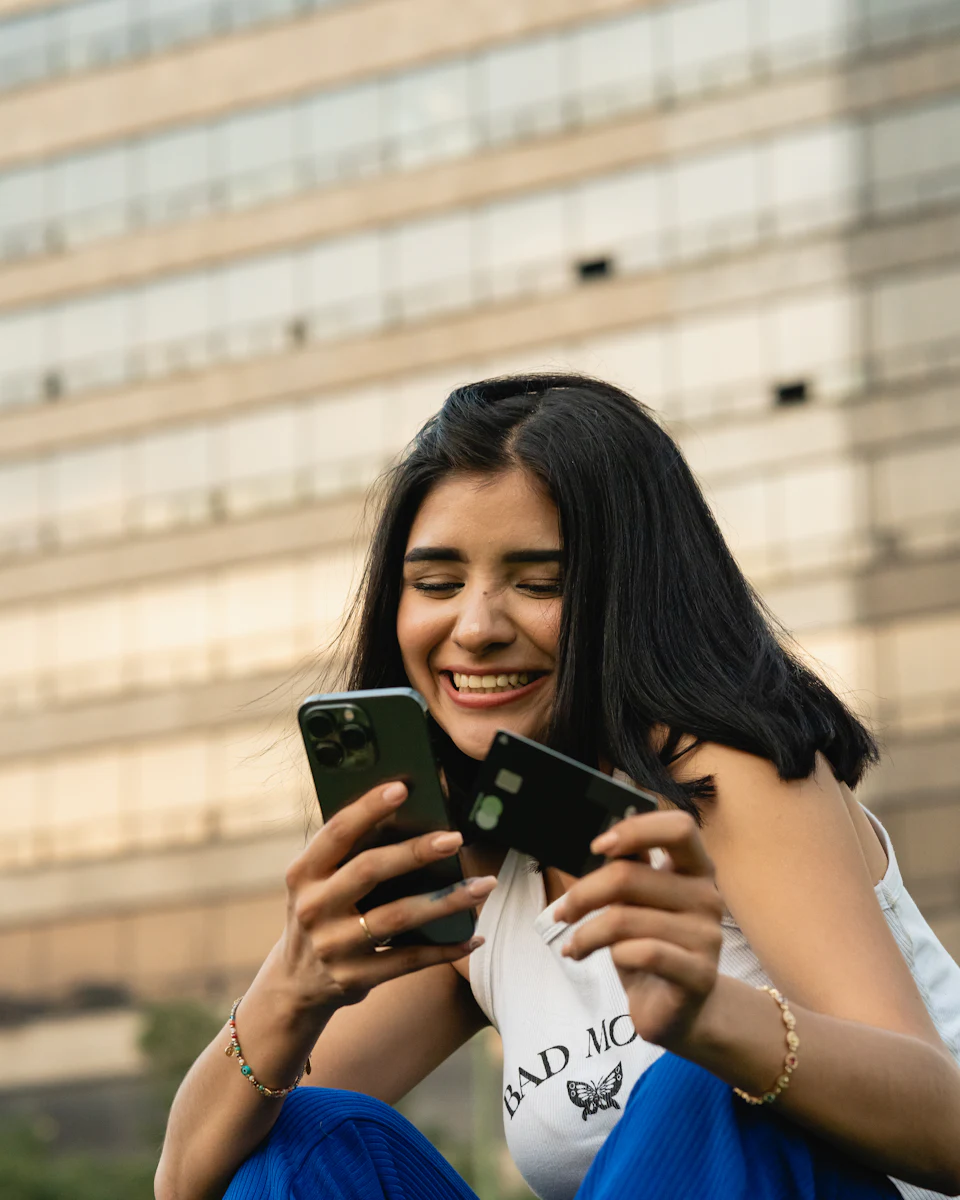 Una adolescente sonríe mientras mira su teléfono.